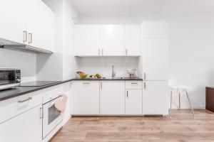a white kitchen with white cabinets and a wooden floor at Enjoy! Ursus in Warsaw