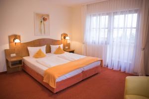 a bedroom with a large bed and a large window at Familienhotel Friedrichshof in Obertrubach