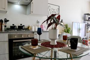 uma cozinha com uma mesa de vidro e um vaso em The Red Portrait at Carlswald em Midrand
