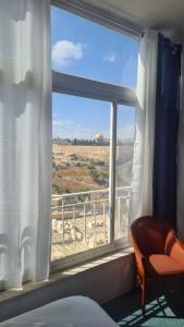 a bedroom with a window with a chair and a view at Jerusalem Panorama Hotel in Jerusalem