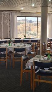 a restaurant with tables and chairs and a large window at Jerusalem Panorama Hotel in Jerusalem