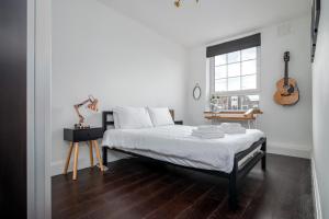 a bedroom with a bed and a guitar on the wall at GuestReady - Modern Chic in Homerton in London