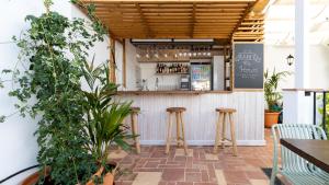 a bar with two stools in a restaurant with plants at Veranera Hostel in Estepona
