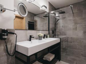 a bathroom with a white sink and a shower at VAYA Residence Galtür Paznaun in Galtür +52 photos