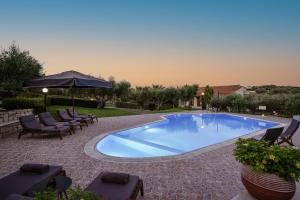 una piscina con sillas y sombrilla en Villas Lefkothea with Large Pool, Playground Area, & Magnificent Views!, en Adelianos Kampos