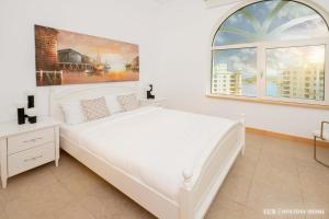 a white bedroom with a white bed and a window at LUX - The Shoreline Penthouse Suite in Dubai