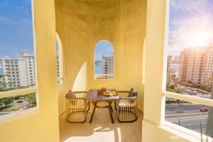 einen Balkon mit einem Tisch und Stühlen sowie einem Fenster in der Unterkunft LUX - The Shoreline Penthouse Suite in Dubai