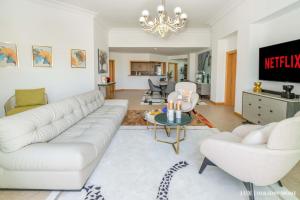 ein Wohnzimmer mit einem weißen Sofa und einem Tisch in der Unterkunft LUX - The Shoreline Penthouse Suite in Dubai