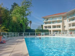 a swimming pool in front of a building at Studio au calme avec piscine, face golf, parking gratuit, tout à pied à 10mn centre ville in Ciboure