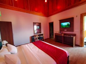 a bedroom with a bed and a tv on the wall at Satopanth The Auli Resort By Royal Collection Hotels in Joshīmath