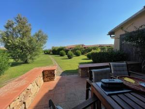 a patio with a wooden bench and a stone wall at Appartamento in villaggio, a 150mt dal mare in San Teodoro