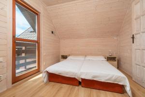 a bed in a room with a large window at Zacisze Morskie in Sarbinowo