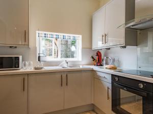 a kitchen with white cabinets and a sink and a window at Spilstead Barn in Sedlescombe