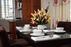 a dining room table with a vase of flowers on it at Hanoi Delica Hotel in Hanoi