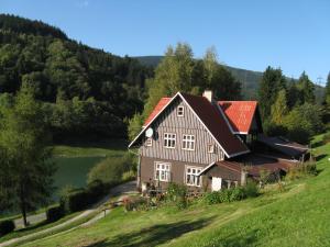 スピンドレルフ・ムリンにあるApartmán 3 Špindlerův Mlýnの川と木のある丘の上の家