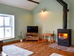 a living room with a fireplace and a television at Keats Barn in Ireby