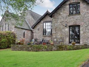 a stone house with a lawn in front of it at The Old School Penallt in Mitchel Troy