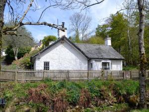 ein weißes Cottage mit einem Holzzaun in der Unterkunft Burnmouth in Balnaboth