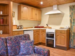 a kitchen with wooden cabinets and a stove top oven at Burnmouth in Balnaboth