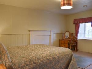 1 dormitorio con cama, escritorio y ventana en Burnmouth en Balnaboth