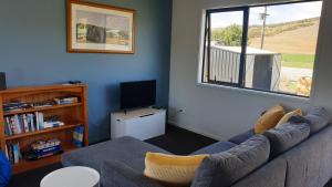 a living room with a couch and a tv at Rough Ridge Cottage ~ your haven in Central Otago in Oturehua