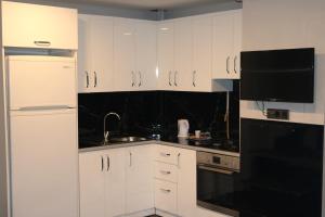 a kitchen with white cabinets and a black appliance at Carpe Diem Suit in Kırac