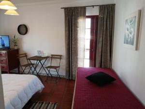um quarto com uma cama, uma mesa e uma janela em Casa Monreal em Reguengos de Monsaraz