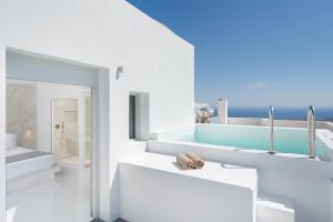 Un baño blanco con bañera y lavabo. en Cycladic Suites & Spa, en Fira