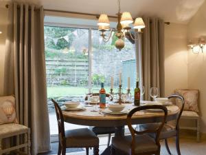 a dining room with a table with chairs and a window at Smiddy Cottage in Aberfeldy