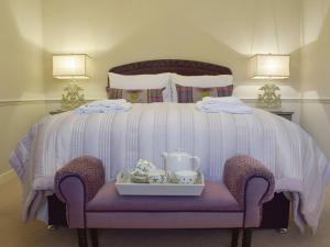 a bed with a purple chair with a tray of tea sets at Smiddy Cottage in Aberfeldy