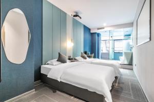 a bedroom with two beds and a mirror at Puzzle Hotel Guangzhou Fenghuang New Village Subway Station in Guangzhou