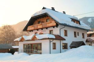 a snow covered house with a balcony on top of it at Frühstückspension Seerose in Weissensee
