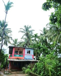 a colorful house with palm trees in the background at Bageecha B&B- Vaayu in Alibaug
