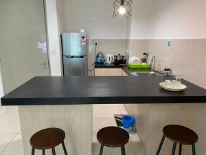 a kitchen with a black counter and two bar stools at KK City Sutera Avenue Opposite Imago by JR Homestay in Kota Kinabalu