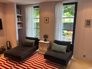 Una sala de estar con un sofá y sillas y ventanas. en Luxe tuinhuis nabij Amsterdam, en Oostzaan