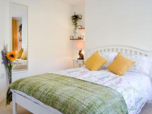 een slaapkamer met een bed met gele kussens en een spiegel bij 3 Old Posting Stables in Gatehouse of Fleet