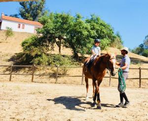 een man die naast een kind op een paard staat bij Monte Do Areeiro in Coruche