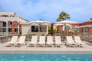 a group of chairs and umbrellas next to a swimming pool at Kyrat Amarac Suites in Cala Millor