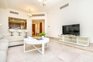 a living room with a white couch and a tv at Bespoke Holiday Homes - Palm Jumeirah- 2 Bedroom with Gym, Beach & Pool Access, Fairmont South in Dubai