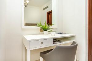 einen weißen Schreibtisch mit einem Spiegel und einem Stuhl in der Unterkunft Bespoke Holiday Homes - Palm Jumeirah- 2 Bedroom with Gym, Beach & Pool Access, Fairmont South in Dubai