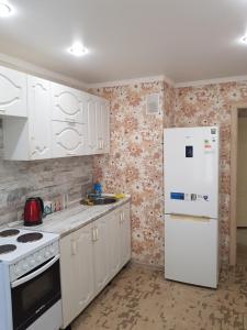 una cucina con armadietti bianchi e frigorifero bianco di квартира a Pavlodar
