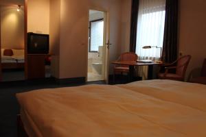 a hotel room with a bed and a desk and a television at Hotel-Gasthof Die Post Brennerei Frankenhöhe in Schillingsfürst