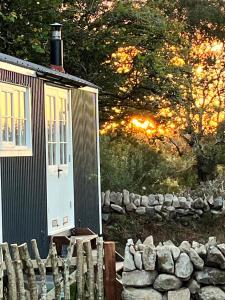 Cabaña pequeña con valla y pared de piedra en The Hazel Hut en Westport