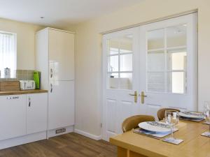 a kitchen with a wooden table with chairs and a white door at Stars Cottage in Moreton
