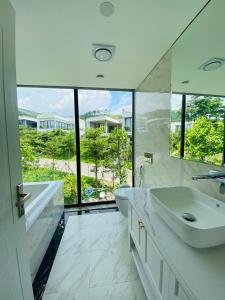 ein Badezimmer mit zwei Waschbecken und einem großen Fenster in der Unterkunft Amun Villa - Venuestay in Vĩnh Phúc