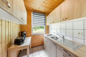 una pequeña cocina con fregadero y ventana en Bungalow 02, en Sondershausen