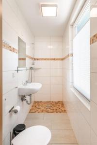 Baño blanco con lavabo y espejo en Bungalow 02, en Sondershausen