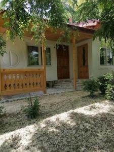 a house with a porch and a wooden door at Casa de oaspeti adorabila aproape de natura in Sărata-Monteoru