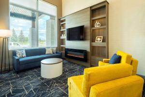 a living room with yellow furniture and a tv at Comfort Inn & Suites in Kingston
