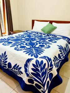 a bed with a blue and white blanket on it at Guest house KupuKupu39 in Kuta